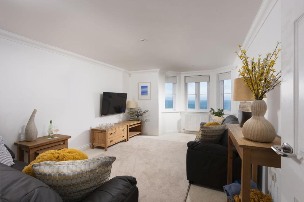 a living room with a couch and a tv at Bay View, Compass Point, Carbis Bay, St Ives in Carbis Bay