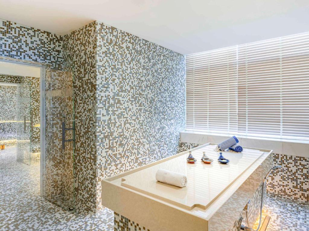 a bathroom with a shower and a table with shoes at Pullman Doha West Bay in Doha