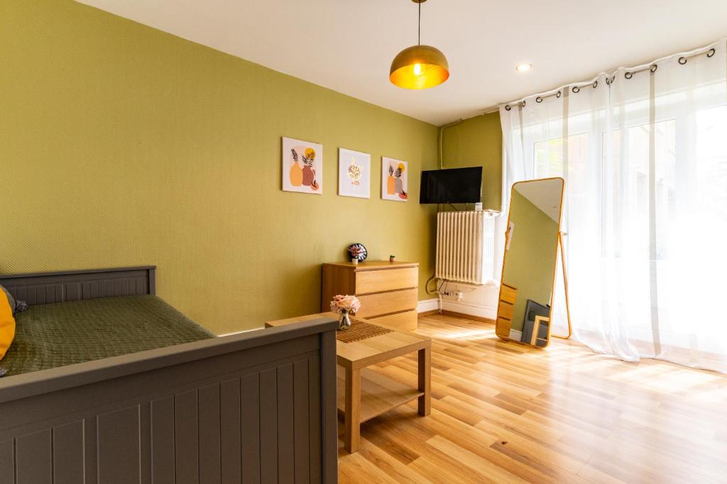 - une chambre avec des murs verts, un lit et une télévision dans l'établissement Le STUDIO 2, à Dijon