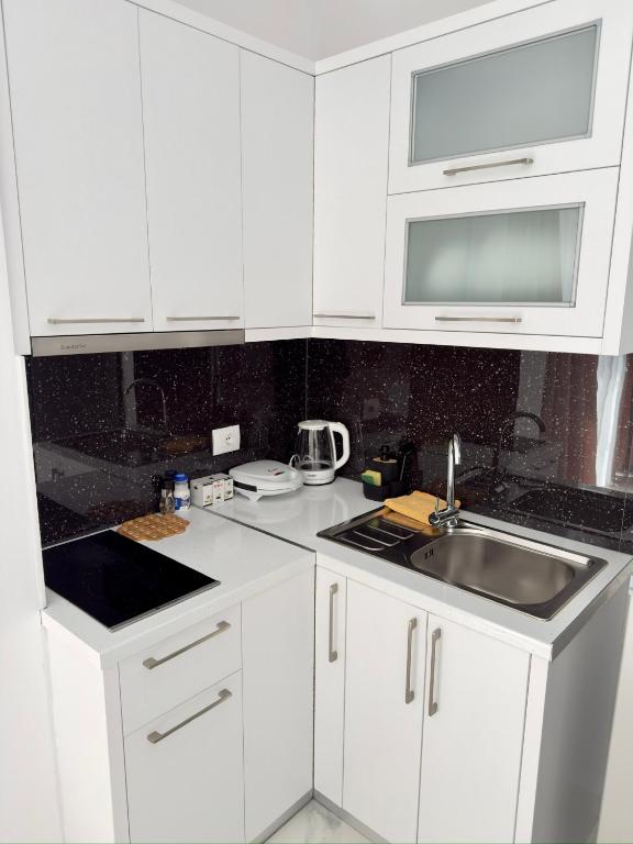 a white kitchen with a sink and a microwave at Villa Denis Ksamil in Ksamil