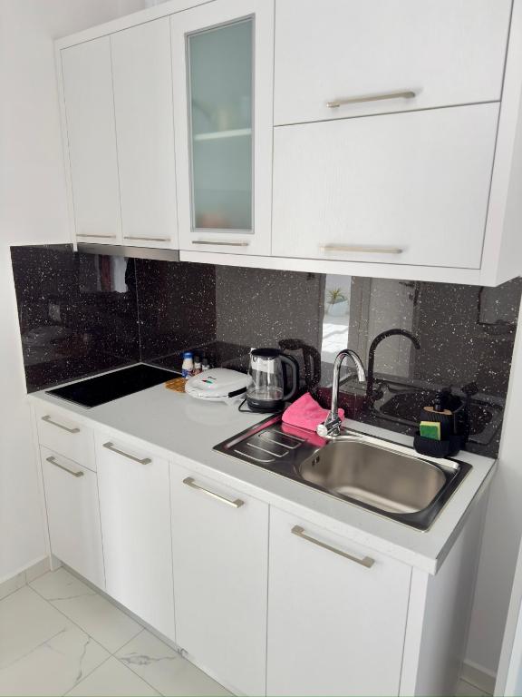 a kitchen with white cabinets and a sink at Villa Denis Ksamil in Ksamil