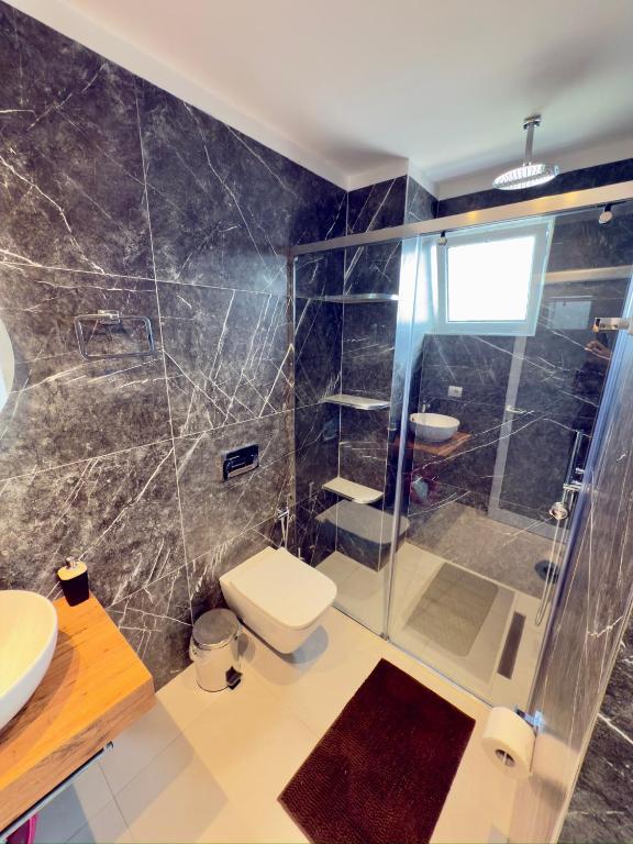 a bathroom with a shower and a toilet and a sink at Villa Denis Ksamil in Ksamil