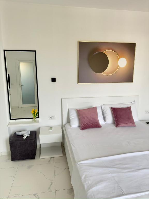 a white bedroom with two beds and a mirror at Villa Denis Ksamil in Ksamil