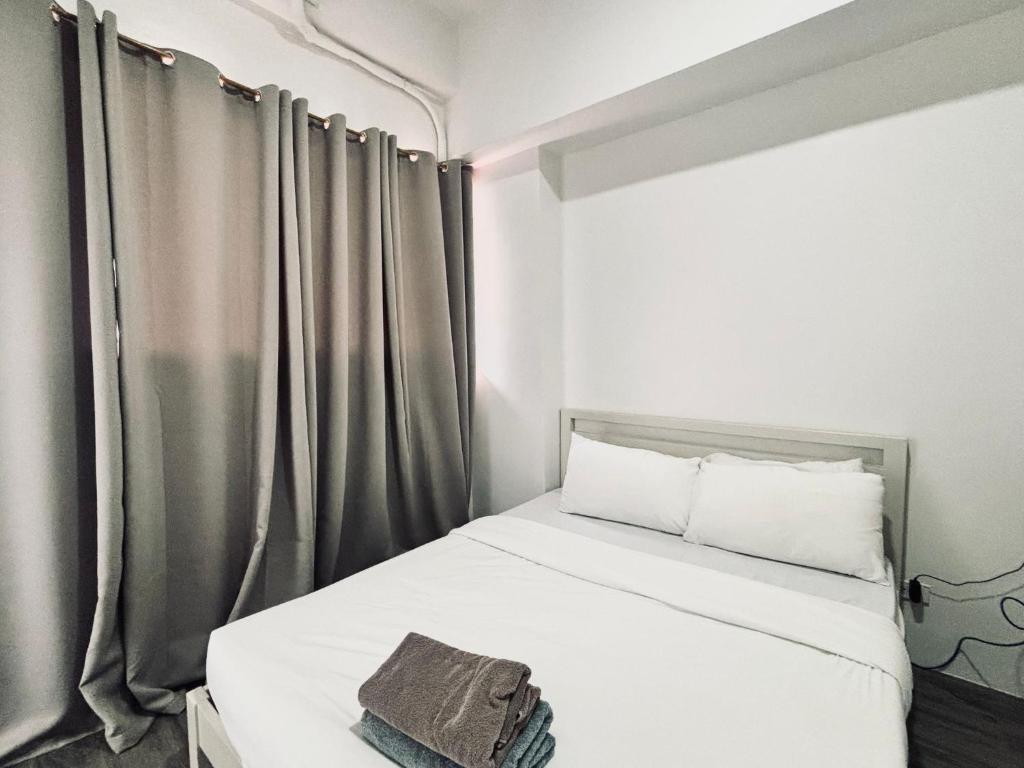a small bedroom with a white bed and curtains at Perfect Stay for Family Friends in Iloilo City