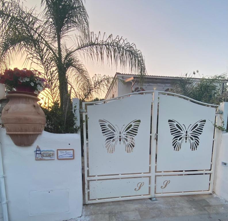 een witte poort met vlinders naast een huis bij Villa al mare in San Felice Circeo