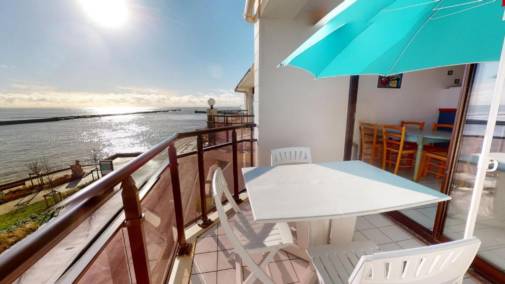 un balcon avec une table, des chaises et un parasol dans l'établissement Le Corsaire Face Mer, à Saint-Gilles-Croix-de-Vie