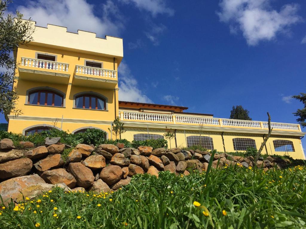 un edificio giallo con una recinzione in pietra di fronte ad esso di Agriturismo Pialza a Sindia