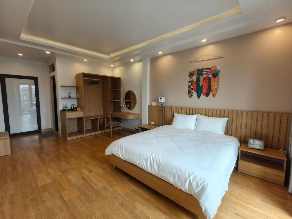 ハイフォンにあるmalela homestay 04の大きな白いベッドと机のある寝室