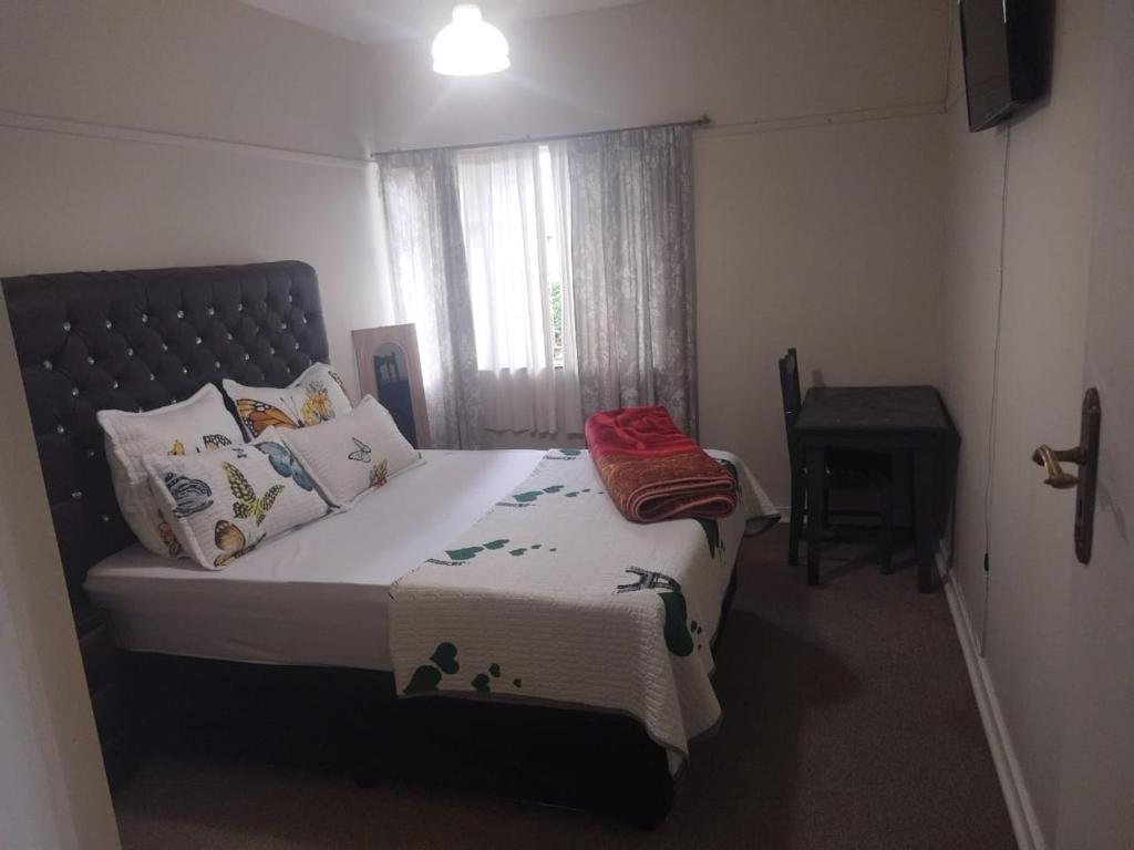 une chambre avec un lit, une fenêtre et une table dans l'établissement J & J Paradise Guest House, à Pietermaritzburg