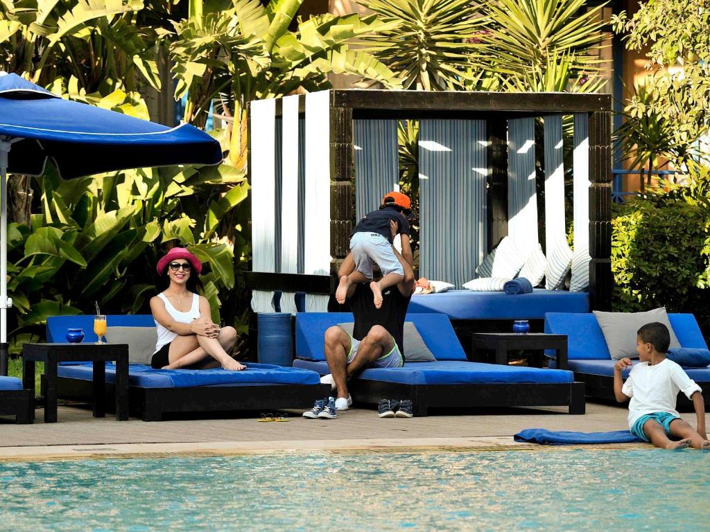 a man holding a child on his shoulders next to a pool at Le Médina Essaouira Thalassa Sea & Spa - MGallery Collection in Essaouira