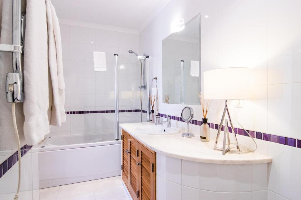 a bathroom with a sink and a tub and a mirror at The View – Santo António Villas, Golf & Spa in Salema