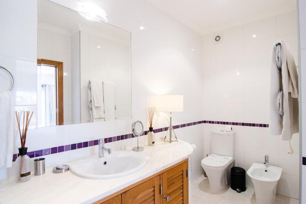 a bathroom with a sink and a toilet and a mirror at The View – Santo António Villas, Golf & Spa in Salema