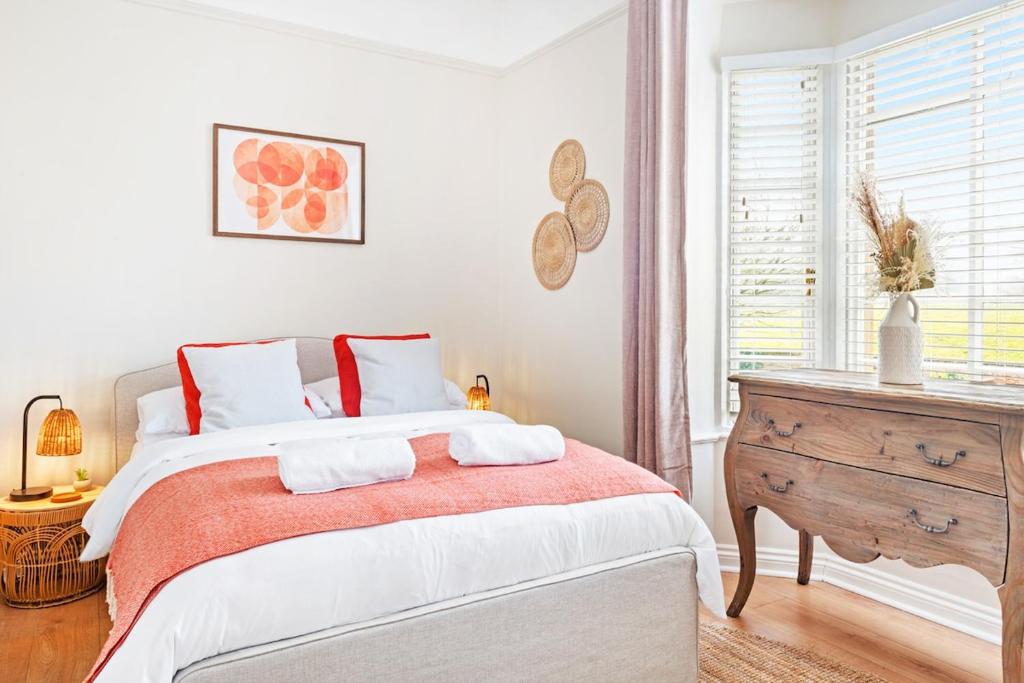 a white bedroom with a large bed and a wooden dresser at The Lodge Cottage in Oxton
