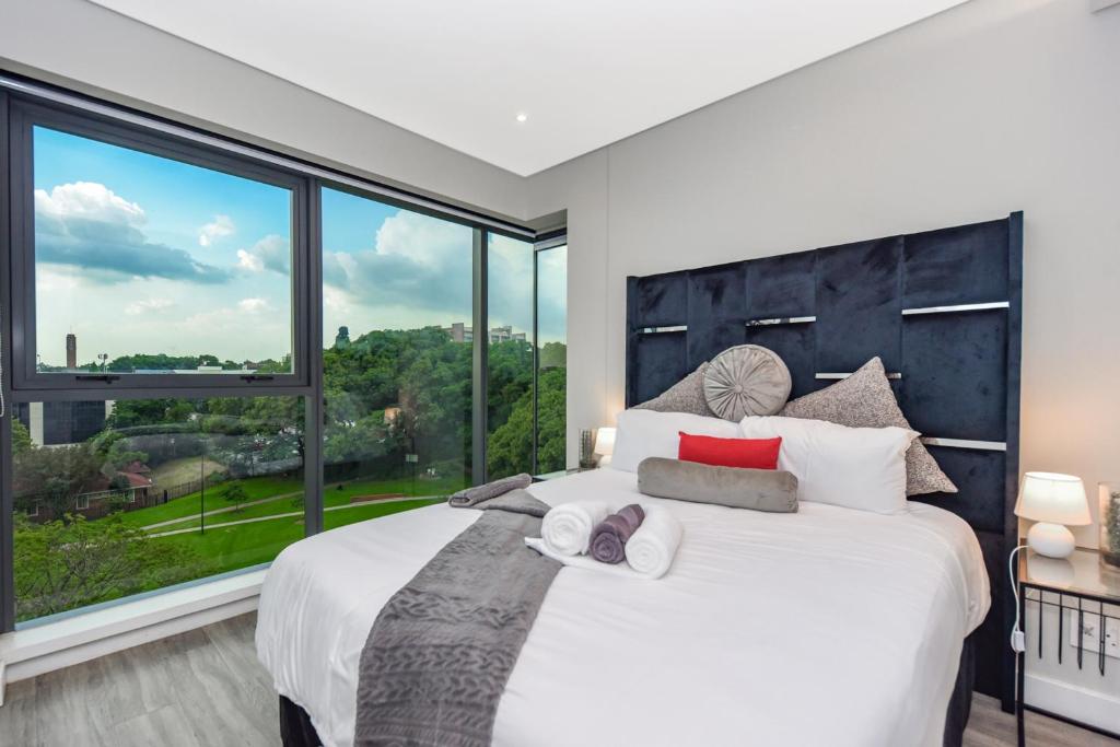 a bedroom with a large bed with a large window at Park Central Residence - Building with Generator in Johannesburg