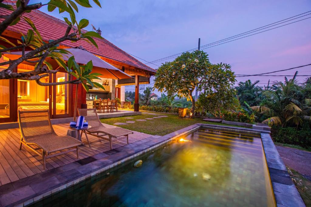 a villa with a swimming pool and two chairs at Jero Kelodan Villa in Tabanan