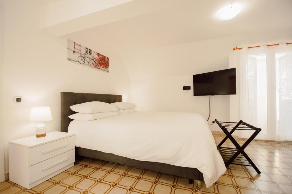 a bedroom with a white bed and a flat screen tv at Queen Elena in Civitavecchia