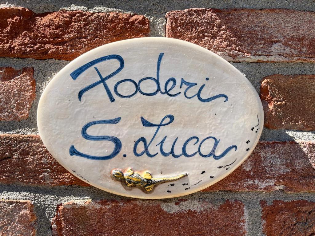 Un cartello su un muro di mattoni con un calabrone sopra. di Poderi S Luca ad Alba