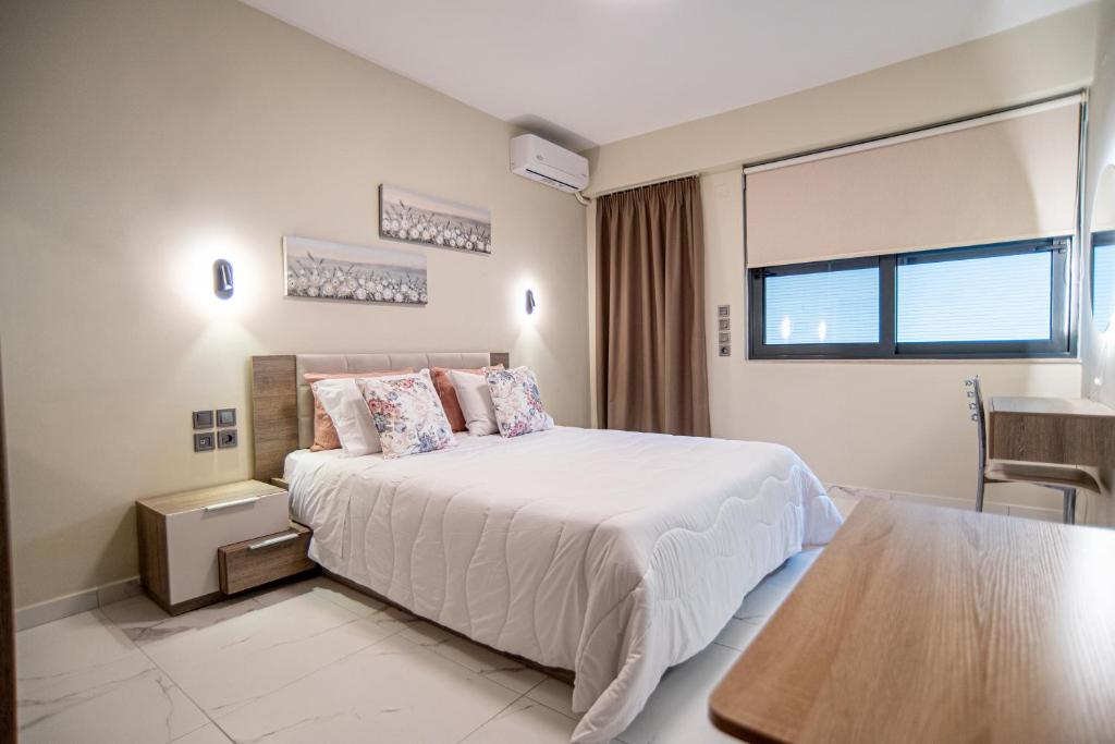 Un dormitorio con una gran cama blanca con una mesa. en Anora Apartment, en Preveza