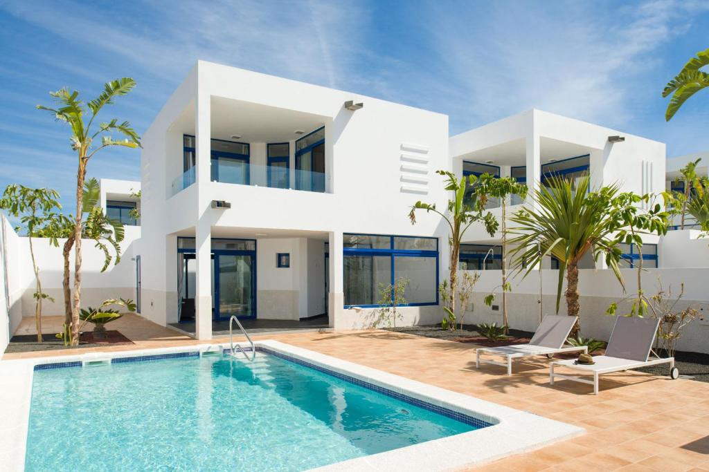 a villa with a swimming pool in front of a house at Villas de la Marina in Playa Blanca