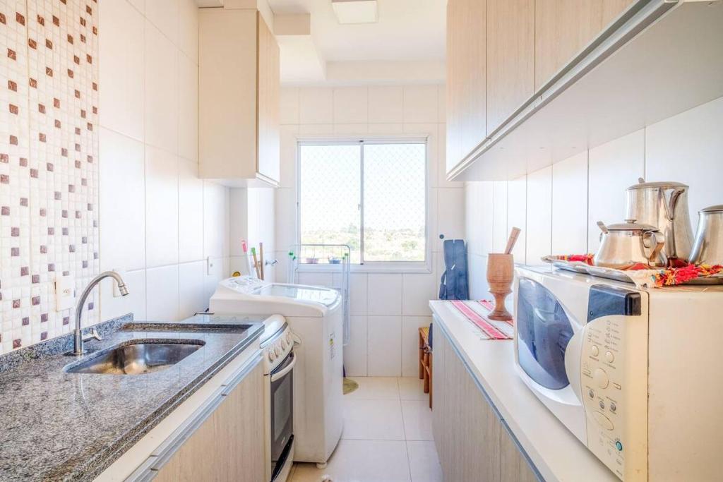 a white kitchen with a sink and a dishwasher at Apartamento encantador San Roman in Bauru