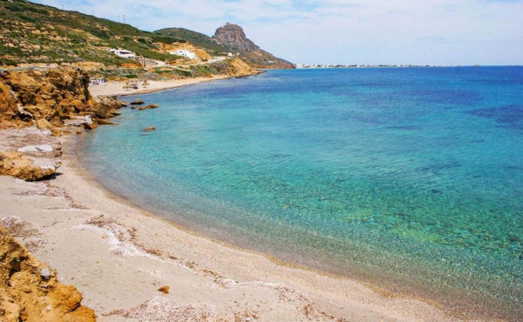a beach with blue water and a rocky coastline at Marilous House - Skyros Beachfront Getaway in Skiros