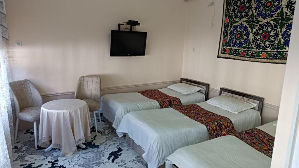 Una habitación con tres camas y un televisor en la pared. en Sogda, en Samarkand