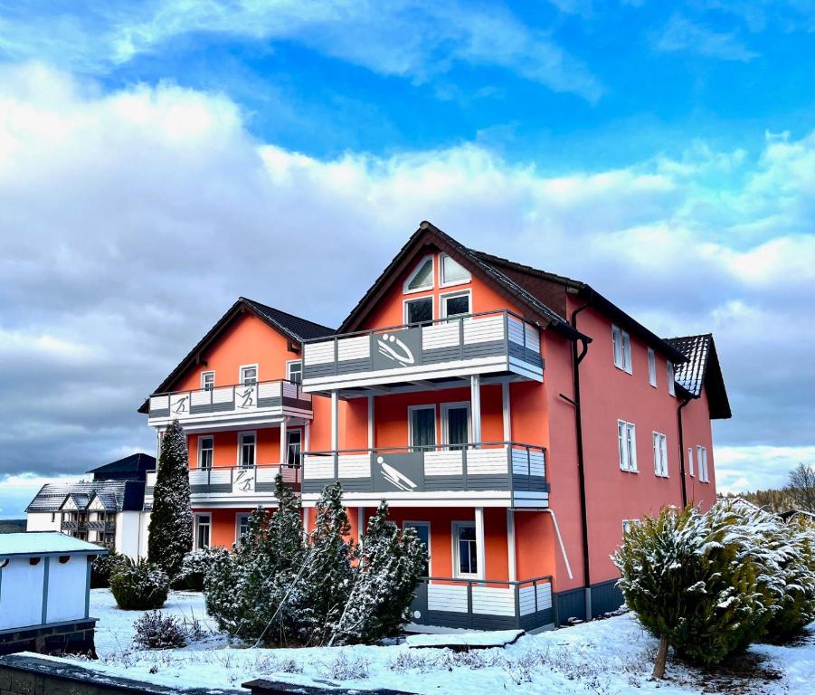 an orange apartment building with snow on the ground at Ferienwohnung Großer Beerberg zum Prinzenweg in Oberhof