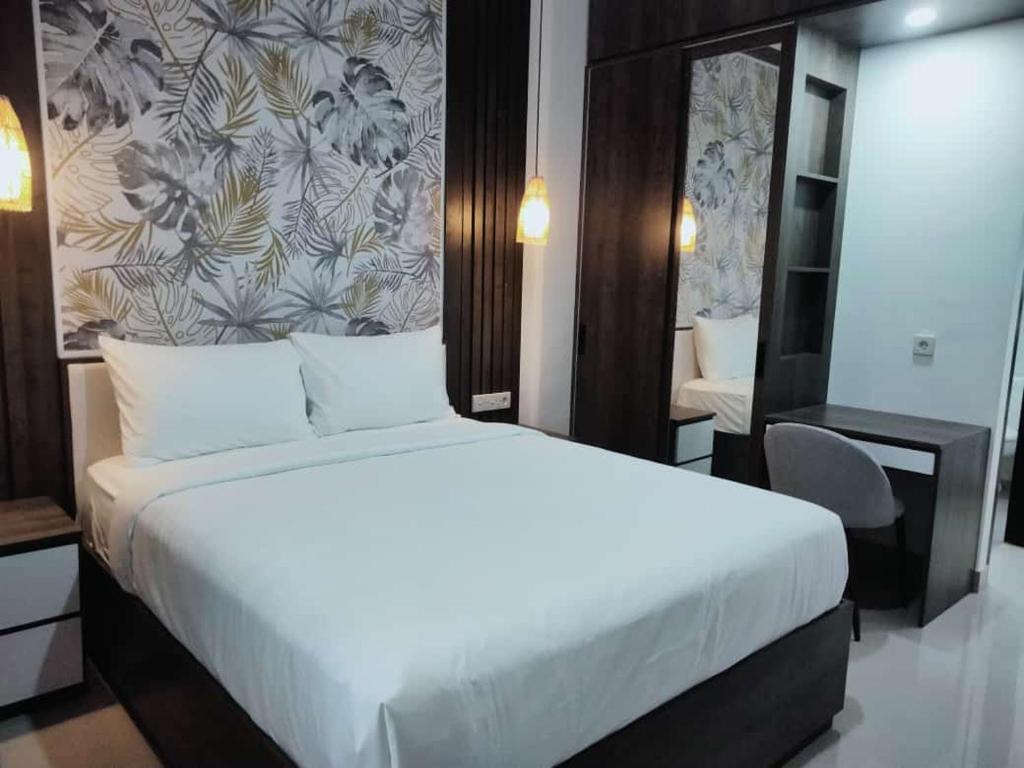 a bedroom with a large white bed and a desk at Apartement Lucky Jimbaran in Jimbaran