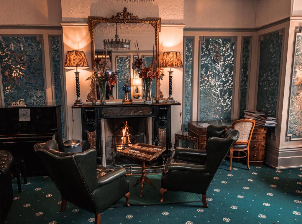 a living room with a fireplace and chairs and a mirror at London Visitors Hotel in London