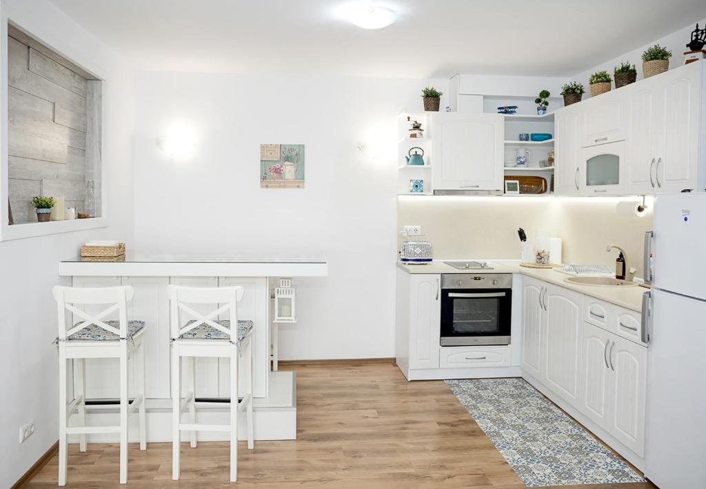 a white kitchen with white cabinets and white appliances at Cozy Seaside Escape - Stylish 1-Bedroom Apartment in Central Balchik by Flat Mаnager in Balchik