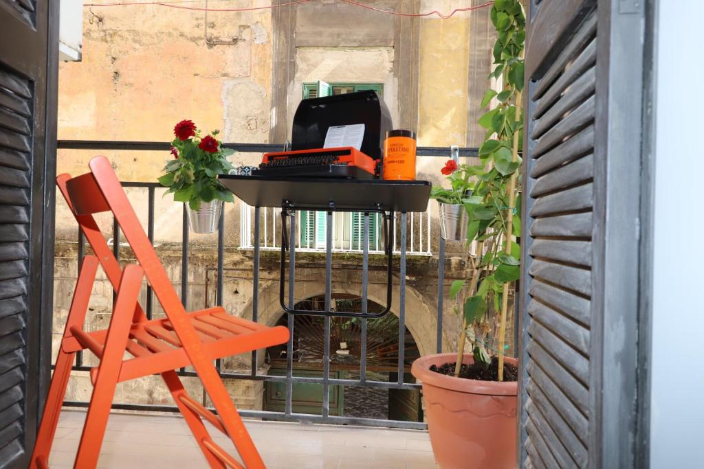 an orange chair and a desk with a computer on a balcony at Bernadette Boutique in Naples