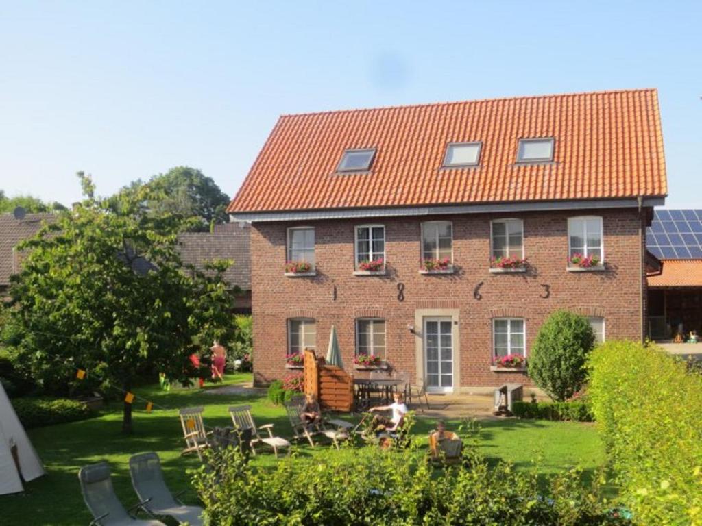 a large red brick building with a yard with chairs at Enkenshof in Nettetal