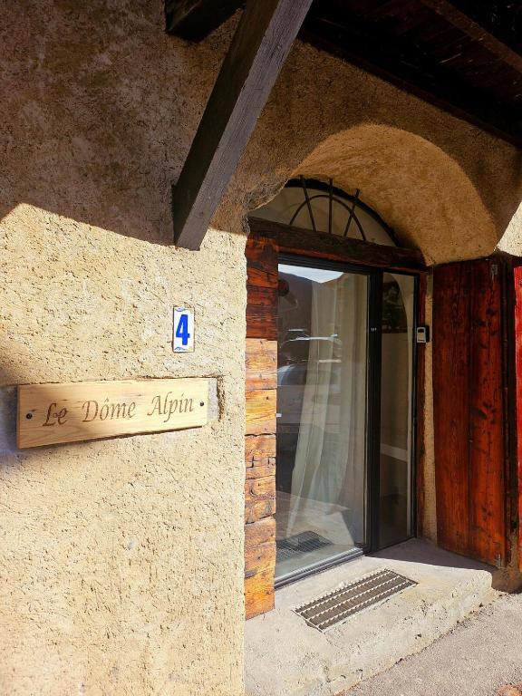 un panneau sur le côté d'un bâtiment avec une porte dans l'établissement Le Dôme Alpin pied des Pistes, à Saint-Chaffrey