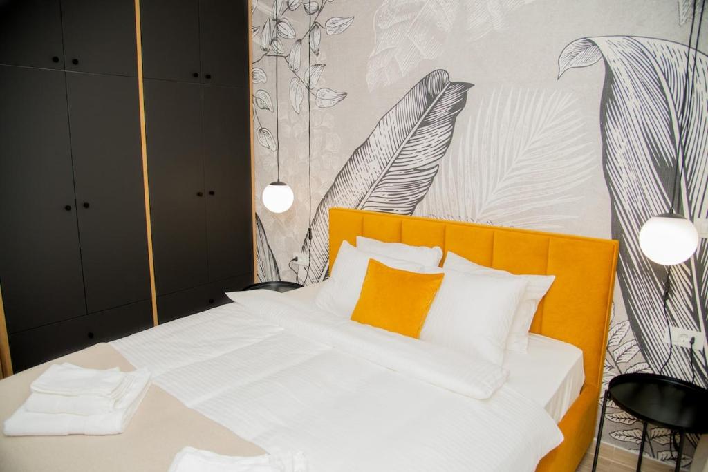 a bedroom with a white bed with an orange pillow at New apartment May in the city center, parking free in Slavonski Brod