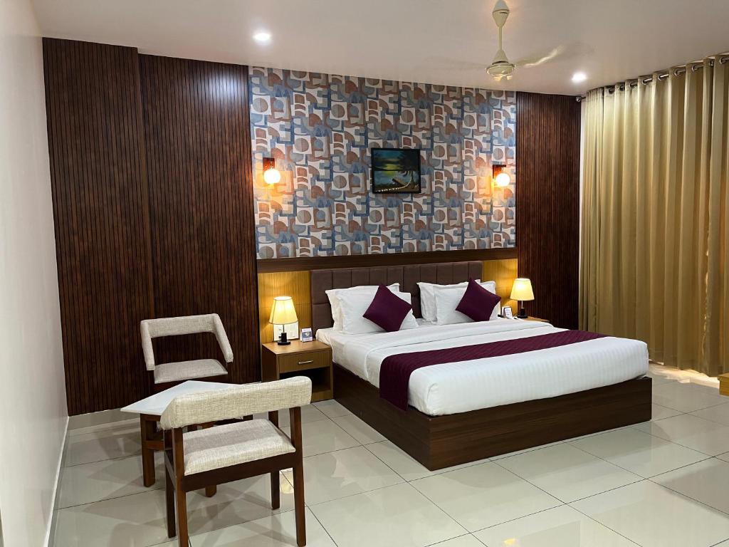 a bedroom with a king sized bed and a chair at Hotel Floral Palace in Kottayam