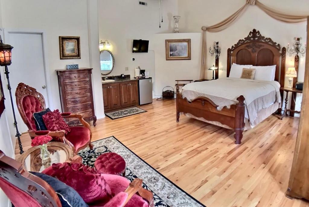 a bedroom with a large bed and wooden floors at Brownstone Rose Suite Parking Walk to Dwntn in Eureka Springs