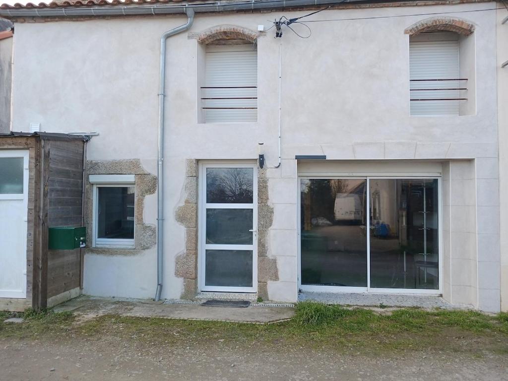 a white building with two windows and a door at Maison de bourg entre Nantes et Cholet in Saint-Crespin-sur-Moine