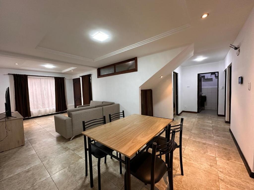 un salon avec une table et des chaises en bois dans l'établissement Departamento Familiar Cómodo Cerca de el Centro, à Cuenca