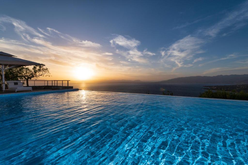 una grande piscina con un tramonto sullo sfondo di Searocks Villas Exclusive Resort a Kalamáta