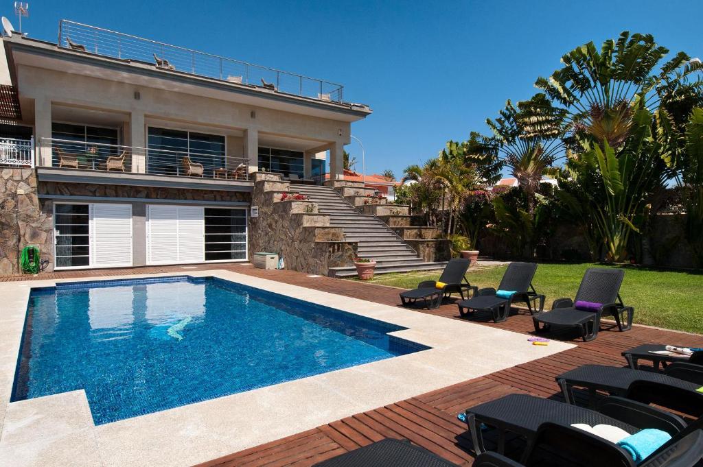 a swimming pool in front of a house at Sonnenland House for 12 by VillaGranCanaria in Maspalomas