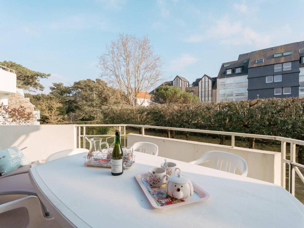 - une table blanche avec une bouteille de vin et des théières dans l'établissement Carnac Plage: Grand T3 58m² avec Wifi et Parking - FR-1-477-133, à Carnac