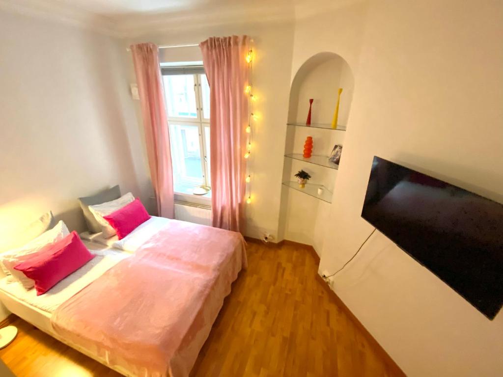 a small room with two beds and a television at Pink Gem, Kamppi in Helsinki