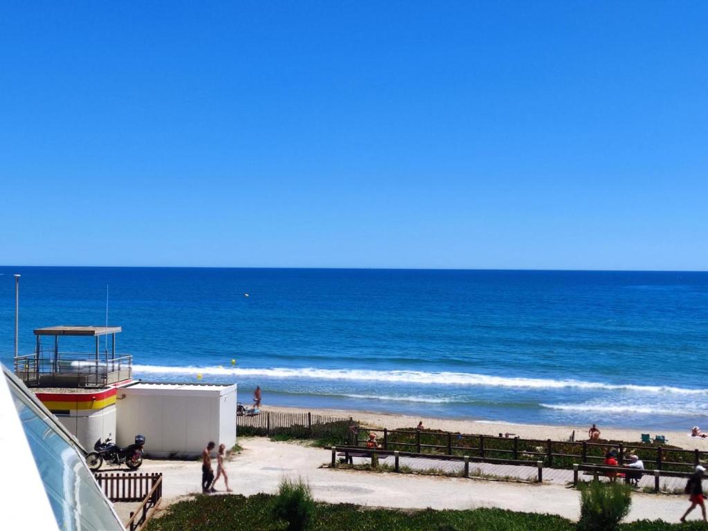 - une plage avec des personnes se promenant sur le sable et l'océan dans l'établissement Studio C28, Héliopolis C au village naturiste, au Cap d'Agde