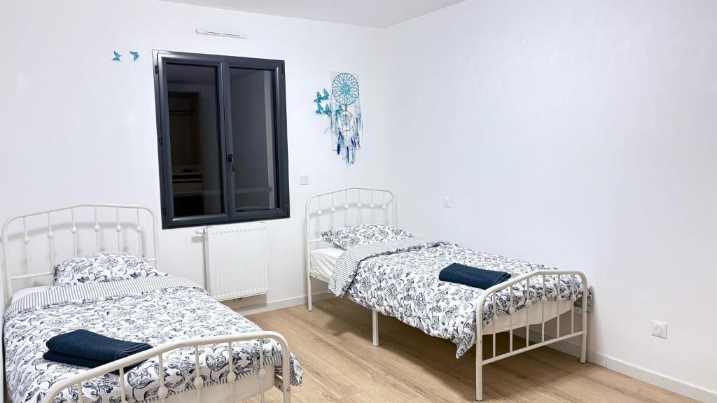 twee bedden in een kamer met witte muren bij Paradis Rouge in Méré