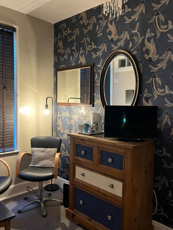 a bedroom with a mirror and a dresser and a chair at Kelston Guest House in Weymouth