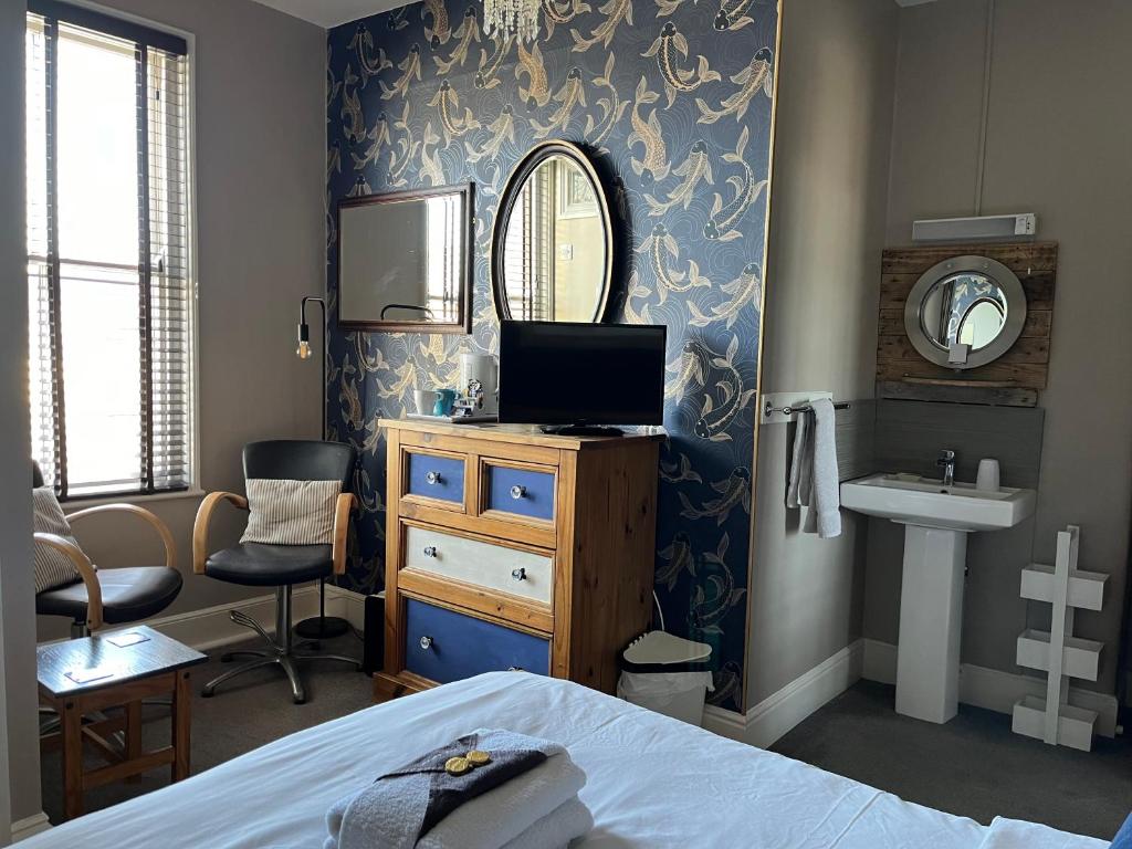 a bedroom with a bed and a sink and a mirror at Kelston Guest House in Weymouth