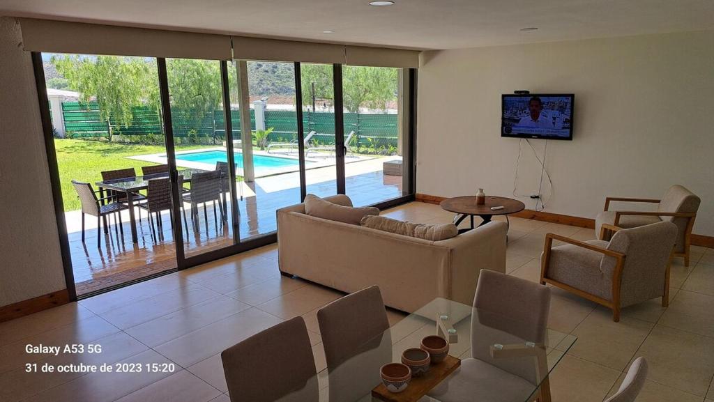 ein Wohnzimmer mit einer Couch, einem Tisch und einem Fernseher in der Unterkunft Laderas de Chacras vista montaña en Barrio privado in Ciudad Lujan de Cuyo