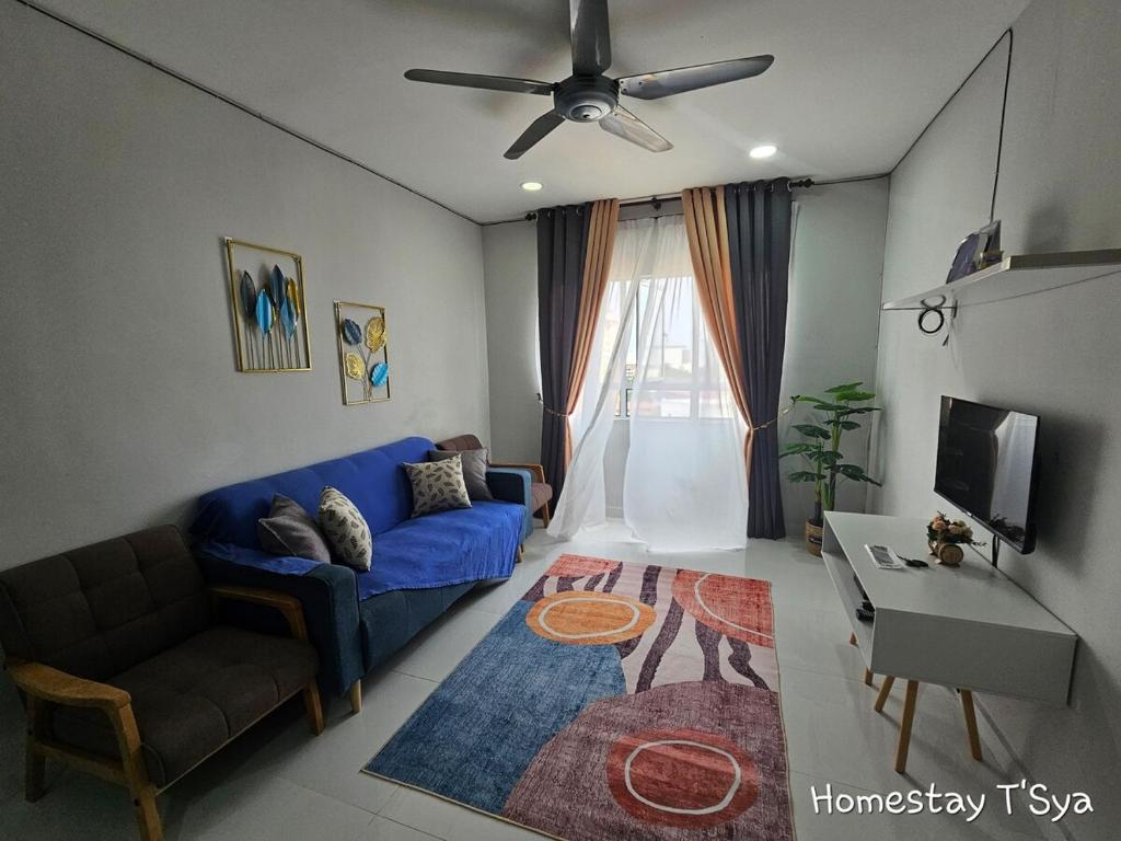 Una sala de estar con un sofá azul y un televisor. en Homestay T'Sya, Batu Buruk, en Kuala Terengganu