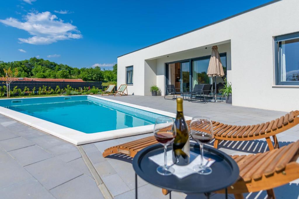 NedeščinaにあるVilla The Pool House, a lush modern villa with a poolのスイミングプールの横のテーブルの上にワイン1本