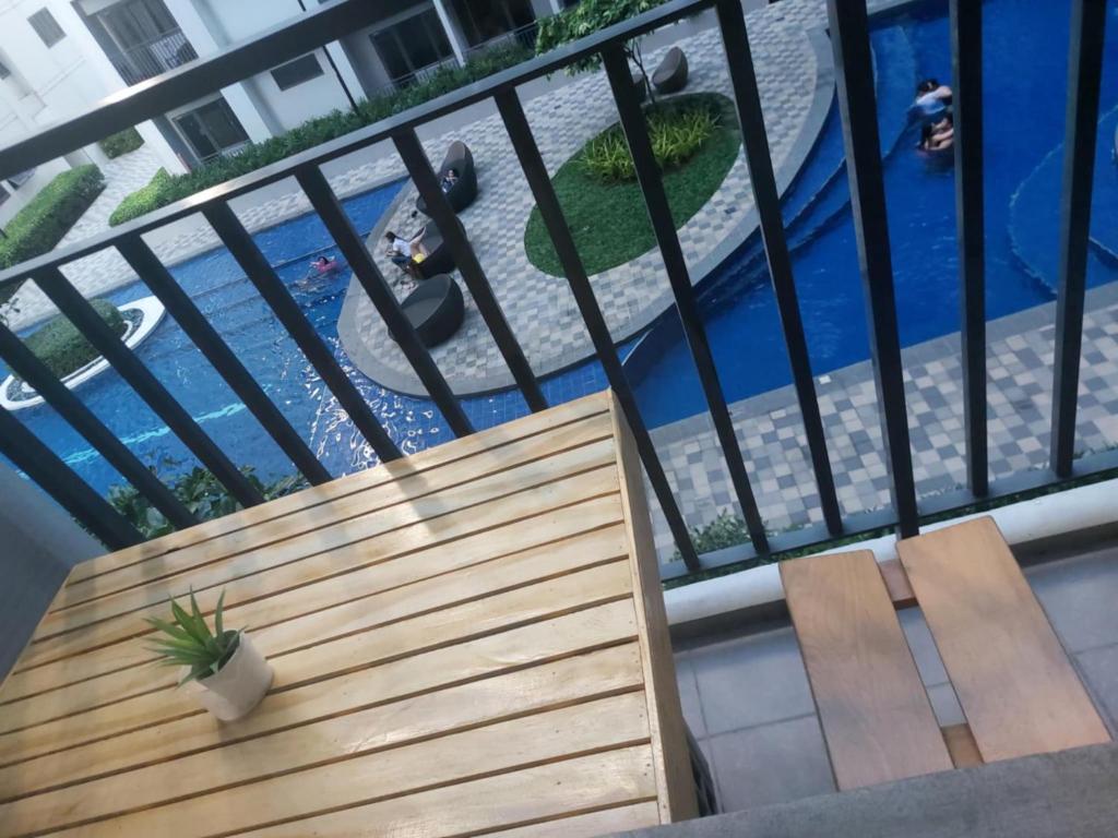 a wooden bench sitting on a balcony with a swimming pool at Overnight @ Shakhbot's in Manila
